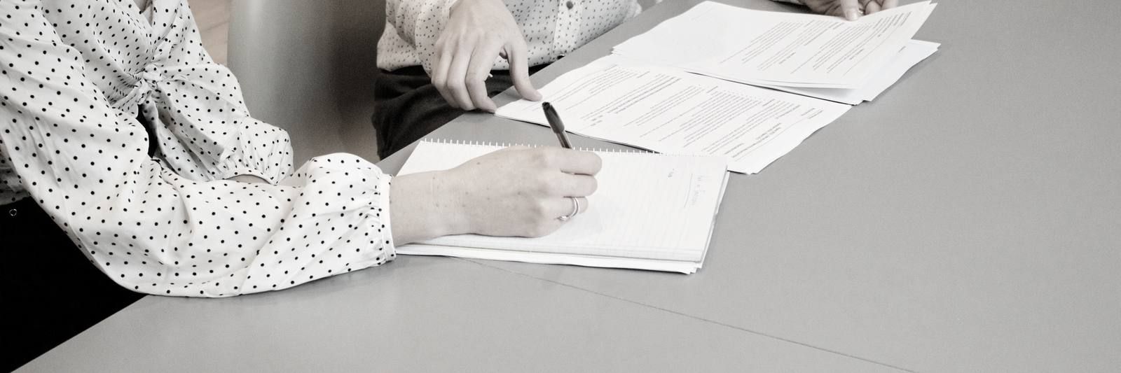 Signing a printed document on an office desk