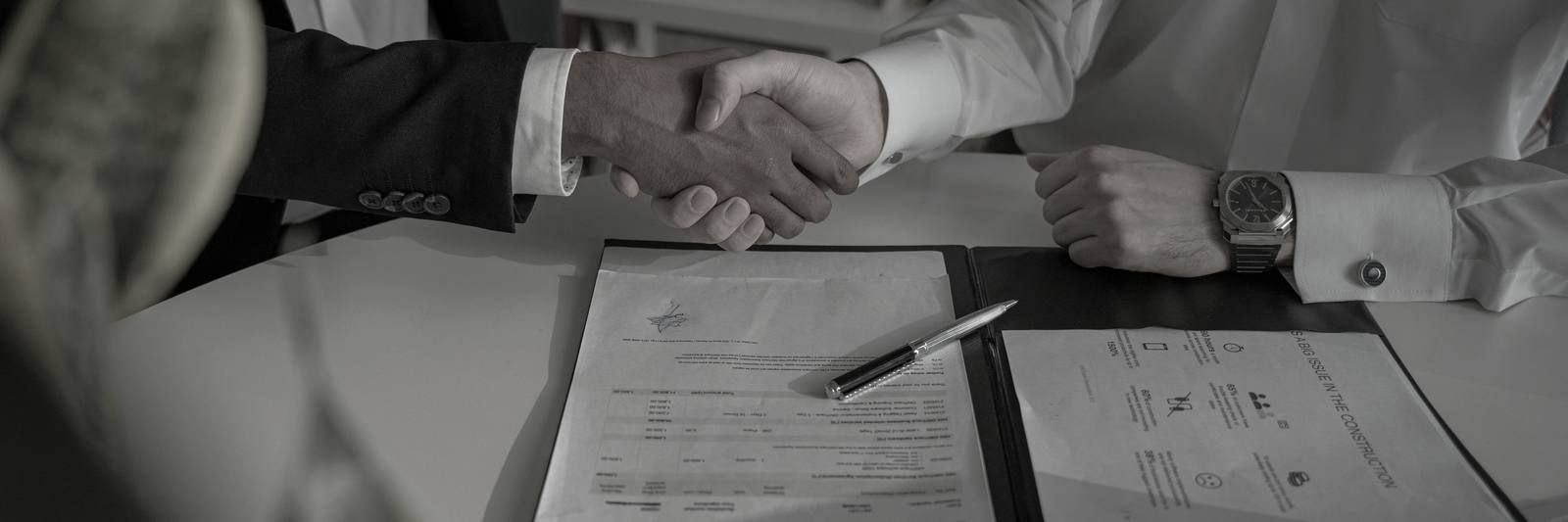 Two people shaking hands over a document