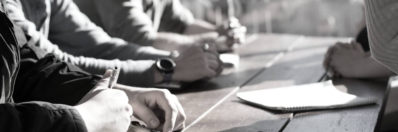 People sitting around a table holding pens